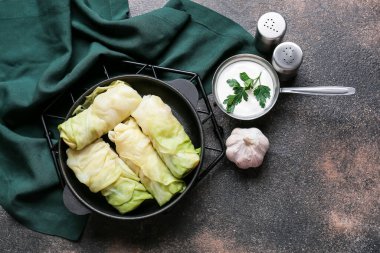 Pişmemiş lahana rulosu ve grunge arkaplanda ekşi krema ile kızartma tavası.