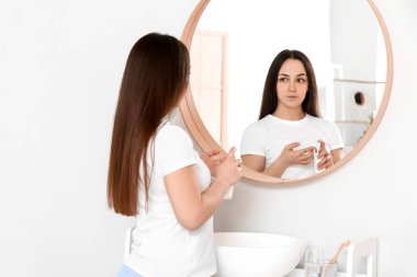 Genç bir kadın banyoya krem sürüyor.