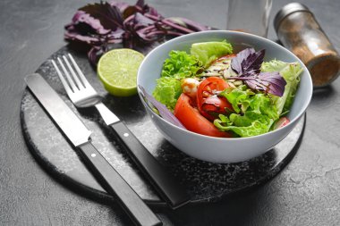 Lezzetli taze salata ve koyu arka planda limonlu kase, yakın plan.