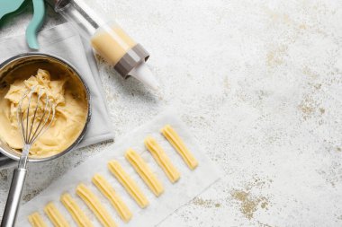 Hafif grunge arka planında krema enjektörü ve pişirilmemiş churros