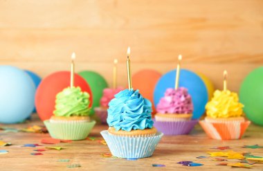 Ahşap arka planda yanan mumları olan lezzetli doğum günü kekleri.