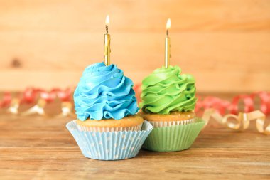 Ahşap arka planda yanan mumları olan lezzetli doğum günü kekleri.