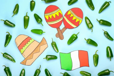 Yeşil jalapeno biberleri ve renkli arka planda Meksika sembolleri.