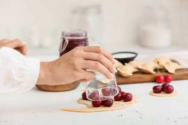 Mutfaktaki masada nefis vişneli börek hazırlayan kadın, yakın plan.