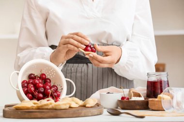 Mutfaktaki masada nefis vişneli börek hazırlayan kadın, yakın plan.
