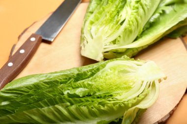 Renkli arkaplanda taze marul olan tahta, yakın plan.