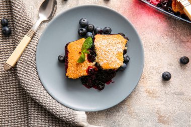 Açık arkaplanda yabanmersinli turta parçaları olan bir tabak.