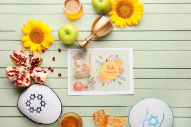 Rosh hashanah (Yahudi Yeni Yılı) için renkli ahşap zemin üzerinde semboller ve kipa olan tebrik kartı