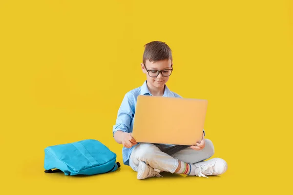 Küçük Okul Çocuğu Renk Arkaplanda Dizüstü Bilgisayar Kullanıyor — Stok fotoğraf