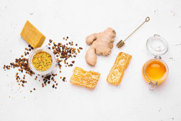 Different bee products with ginger on white background