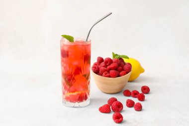 Bir bardak lezzetli limonata ve arka planda ahududulu kase.