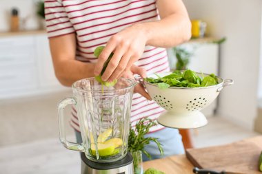 Genç adam mutfakta sağlıklı yeşil smoothie hazırlıyor.