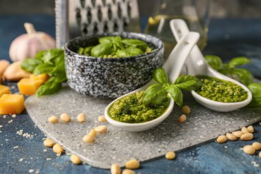 Arka planda taze pesto soslu kase ve kaşıklar.