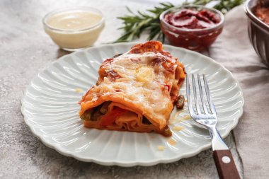 Lezzetli sebze lazanyalı tabak ve arka planda soslar, yakın plan.