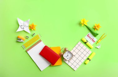 Kırtasiye malzemesi, origami ve kağıt içeren alarm saati renk arkaplanında öğretmenle