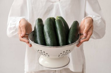 Hafif arka planda taze kabak kabaklı süzgeç tutan kadın, yakın plan.