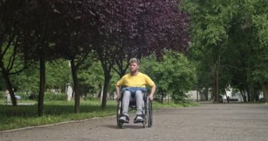 Dışarıda tekerlekli sandalyede genç bir adam var.