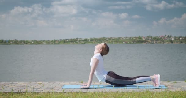 Mujer Joven Deportiva Practicando Yoga Cerca Del Río — Vídeos de Stock