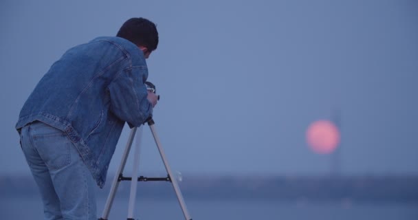 Jongeman Die Avonds Door Een Telescoop Naar Maan Kijkt — Stockvideo