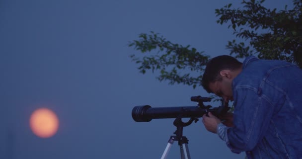 Молодой Человек Смотрит Луну Через Телескоп Вечером — стоковое видео