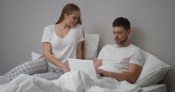 Kadın Kocasıyla Yatakta Flört Ediyor Adam Meşgul Dizüstü Bilgisayar Kullanıyor — Stok video