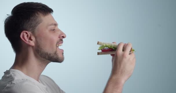 Mann Isst Leckeres Sandwich Auf Farbigem Hintergrund — Stockvideo