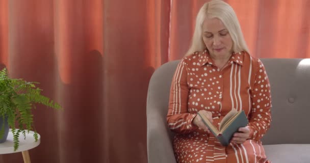 Vacker Mogen Kvinna Läser Bok Hemma — Stockvideo