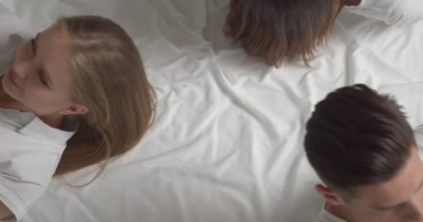 Stilig Ung Man Och Två Vackra Kvinnor Liggande Sängen Ovanifrån — Stockvideo
