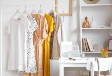 Modern iş yeri ve askı, ışık duvarına yakın kıyafetler.