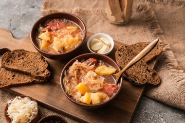 Lezzetli lahana turşusu çorbası ve arkaplanda taze ekmek dilimleri.