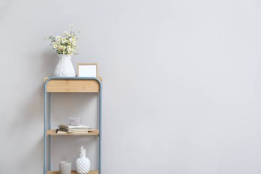 Lamba duvarına yakın raflarda papatya ve dekor olan vazo.