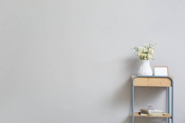 Vazo papatya çayı ve çerçeve ışıklı duvarın yanında.