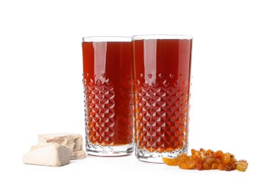 Beyaz arka planda bir bardak taze kvass, kuru üzüm ve maya.