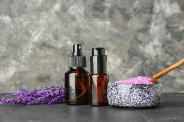 Koyu arkaplanda lavanta yağı, deniz tuzu ve çiçek içeren kompozisyon