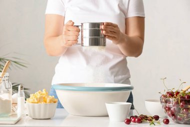 Kadın masada vişneli turta için hamur hazırlıyor.