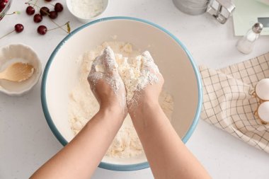 Kadın masada vişneli turta için hamur hazırlıyor.