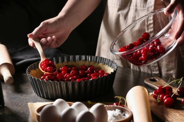 Masada vişneli turta pişiren kadın.