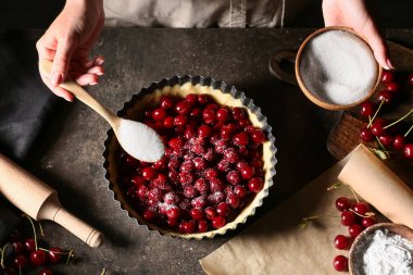 Masada vişneli turta pişiren kadın.