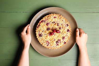 Renkli ahşap arka planda vişneli turtası olan kadın.