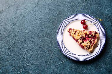 Koyu arkaplanda bir parça vişneli turta.