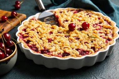 Koyu arkaplanda lezzetli vişneli turta pişirme, yakın plan.