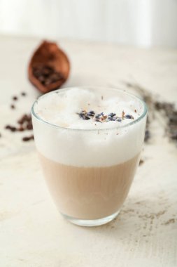Bir bardak lavantalı latte ve arka planda çiçekler.