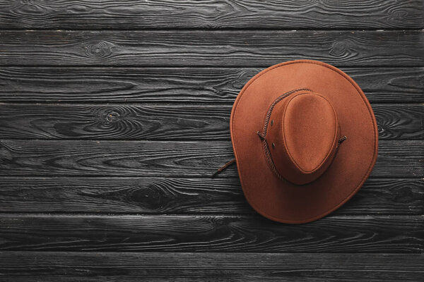 Stylish cowboy hat on dark wooden background