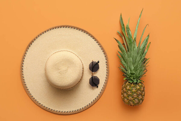 Stylish hat, sunglasses and pineapple on color background