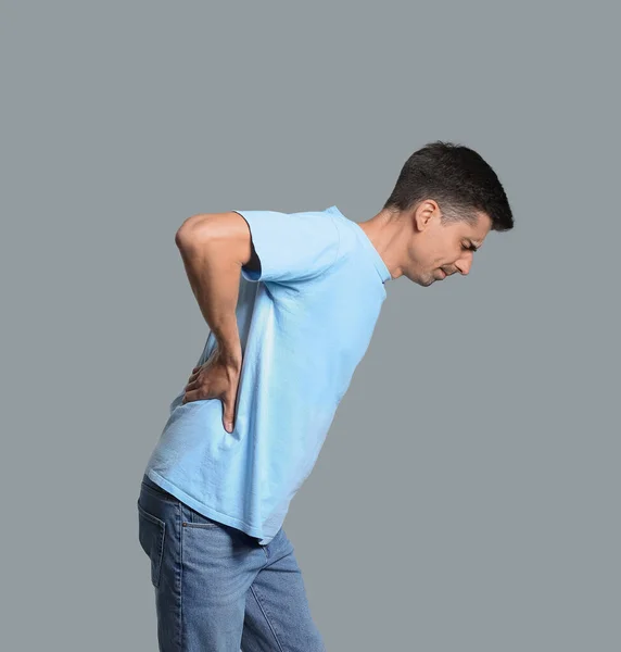 Young man suffering from flank pain on grey background Stock Photo