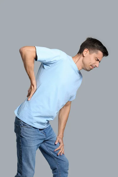 Young Man Suffering Back Pain Grey Background — Stock Photo, Image