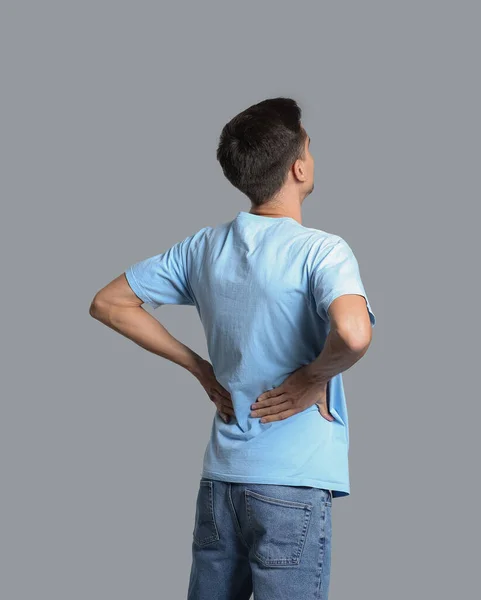 Young Man Suffering Back Pain Grey Background — Stock Photo, Image