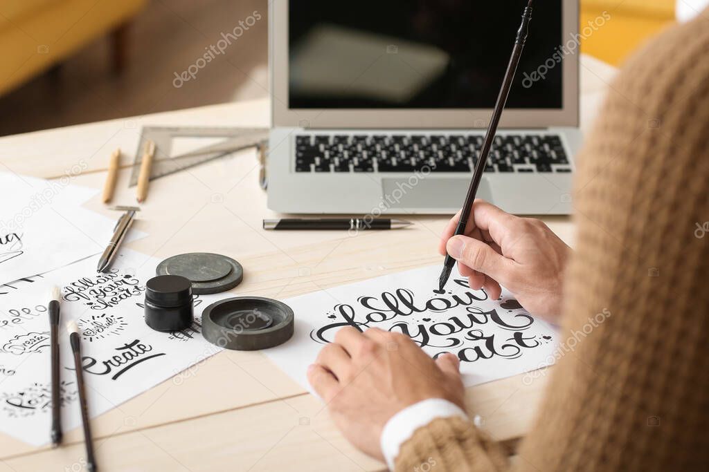 Young male calligrapher working in office, closeup
