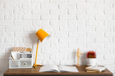 Lambalı masa, düzenleyici ve tuğla duvarın yanındaki defterler.