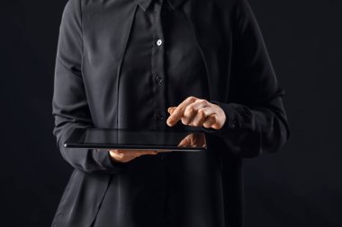 Koyu arkaplanda tablet bilgisayar kullanan genç bir kadın